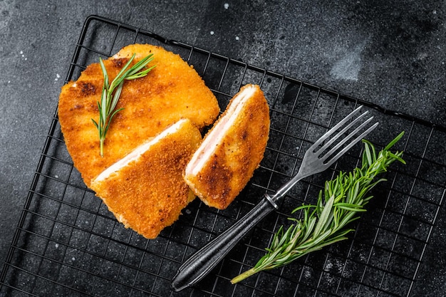 Photo escalope de filet de schnitzel cordon bleu avec jambon et fromage fond noir vue de dessus