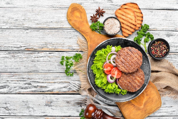 Escalope frite pour burger aux légumes Dans une assiette noire sur un fond en bois Vue de dessus Espace libre pour votre texte Mise à plat