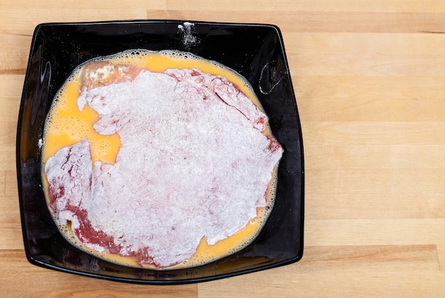 Escalope de veau panée dans de la farine et des œufs dans un bol