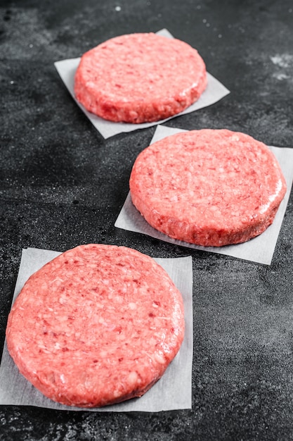 Escalope de viande hachée crue, hacher le boeuf. Galettes de burger sur fond noir. Vue de dessus