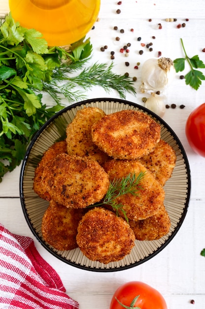 Escalopes maison juteuses (boeuf, porc, poulet) sur un fond en bois blanc.