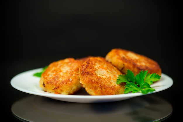 Photo escalopes de poisson frites cuites dans une assiette avec des herbes isolées sur fond noir