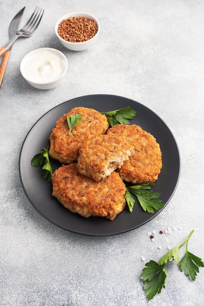 Escalopes de sarrasin au fromage et persil sur une plaque noire sur fond gris clair