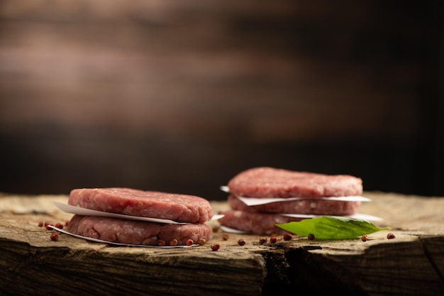 Escalopes de steak de burger de viande de boeuf cru et fond en bois de poivron rouge sec