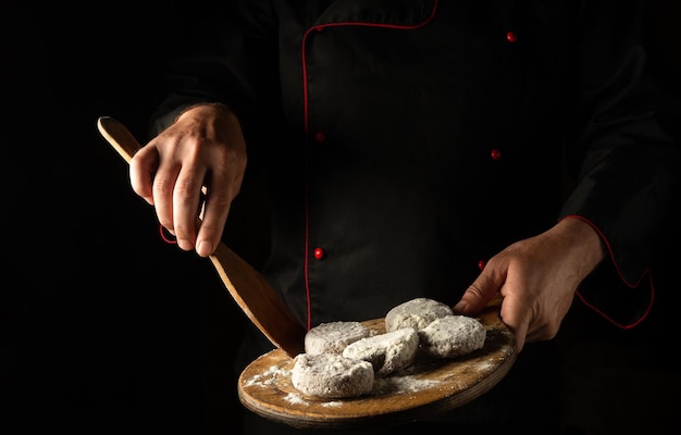 Escalopes de viande en farine sur une planche à découper entre les mains d'un chef Espace libre pour la publicité sur fond noir