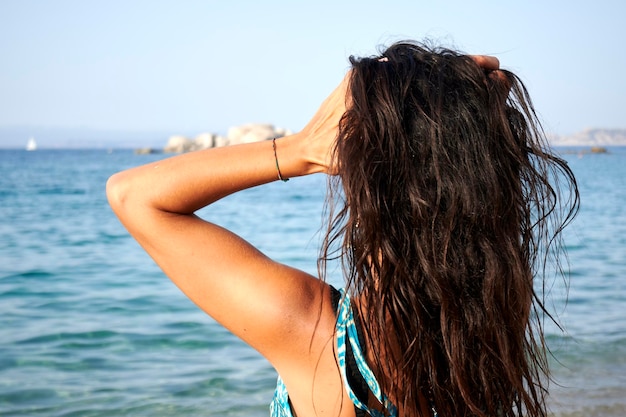 Escapade à la plage ensoleillée Femme aux cheveux bruns regardant l'horizon en profitant de la détente