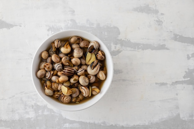 Escargots bouillis dans un bol blanc sur céramique