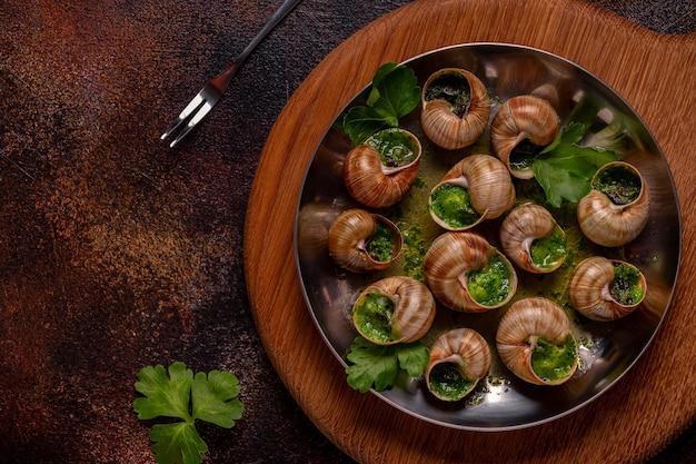 Escargots de Bourgogne Escargots à l'huile d'ail aux herbes dans une plaque de métal