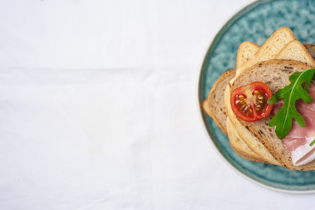 Espace copie, disposition à plat de délicieux morceaux de pain frais avec jambon tomates et salade à la roquette