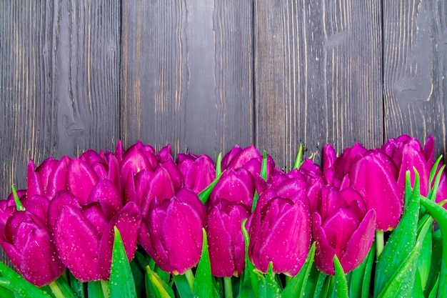 Espace copie de la journée de la femme avec des tulipes rose vif sur un fond en bois noir, textures