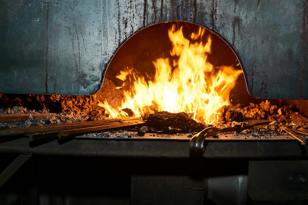 L'espace intérieur du four de forgeron avec un feu brûlant et des flans métalliques s'y réchauffant