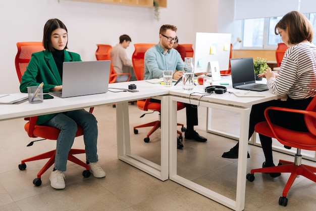 Espace ouvert de bureau d'entreprise moderne avec des employés masculins et féminins occupés utilisant des ordinateurs portables