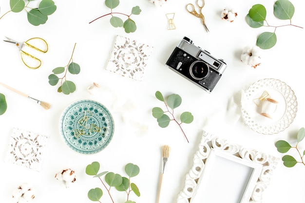 Espace de travail avec des accessoires de feuilles d'eucalyptus sur fond blanc vue de dessus à plat