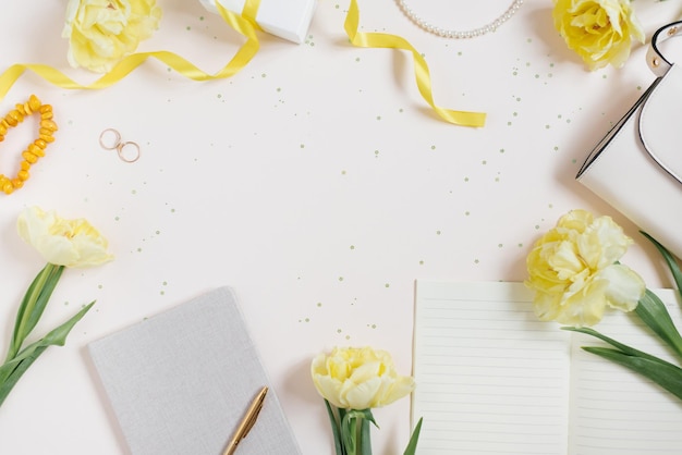 Espace de travail d'un blogueur à la mode avec un accessoire féminin produits de beauté tulipes jaunes fleurs