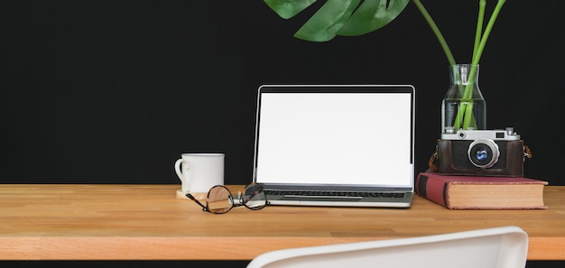 Espace de travail branché avec ordinateur portable à écran blanc et fournitures de bureau sur table en bois