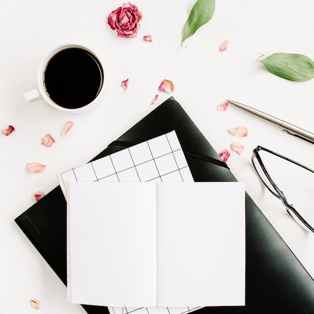 Espace de travail de bureau blanc avec des feuilles vierges et vertes de papier