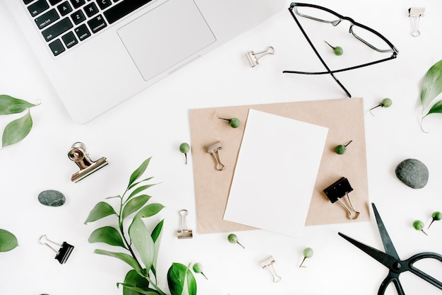 Photo espace de travail de bureau blanc avec des feuilles vierges et vertes de papier