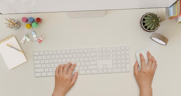 Espace de travail de bureau blanc moderne avec une main féminine tapant sur une vue de dessus de clavier d'ordinateur