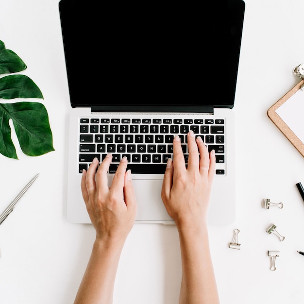 Espace de travail de bureau à domicile avec les mains travaillant sur le clavier de l'ordinateur portable