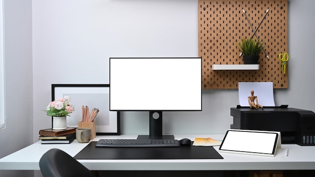 Espace de travail de bureau à domicile avec ordinateur, tablette numérique et fournitures de bureau sur tableau blanc.