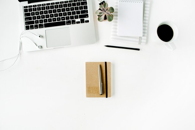 Espace de travail de bureau à domicile plat avec ordinateur portable, agenda, café, succulentes et écouteurs, sur blanc.