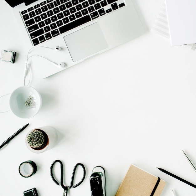 Espace de travail de bureau à domicile à plat avec ordinateur portable, agenda, succulentes et accessoires sur blanc