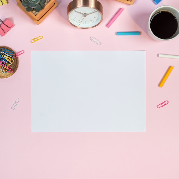 Photo espace de travail de bureau féminin avec maquette de papier blanc sur fond rose.