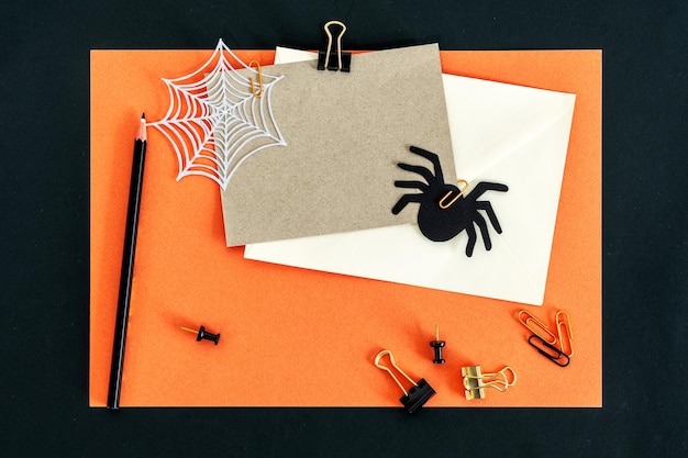 Espace de travail de bureau sur le thème Automne Automne Halloween avec des clips de crayon d'enveloppe de carte sur orange élégant