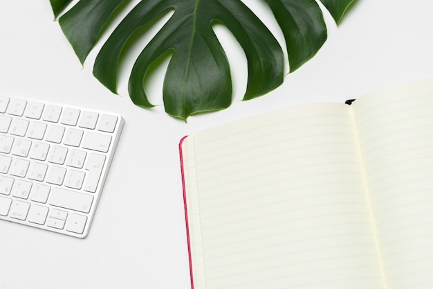 Espace de travail avec clavier, feuille de palmier et accessoires. Mise à plat, espace de copie vue de dessus