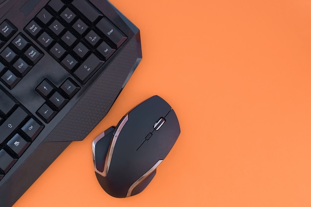 Espace de travail avec un clavier et une souris sur fond orange. Copyspace