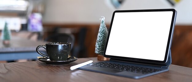 Espace de travail confortable avec tablette informatique, tasse à café et arbre de Noël sur table en bois