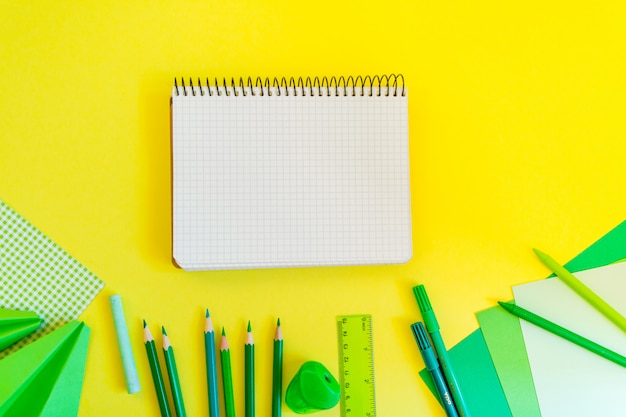 Photo espace de travail créatif, à la mode, minimaliste, à l'école ou au bureau avec fournitures écologiques et cahier à spirale sur fond jaune