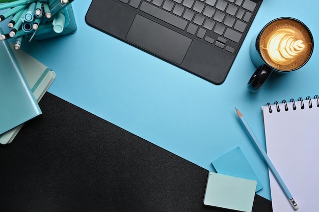 Espace de travail créatif avec tasse à café et ordinateur portable tablette sur fond bleu