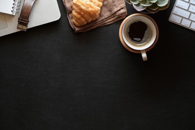 Espace de travail en cuir foncé avec une tasse de café, des fournitures de bureau et un espace de copie noir