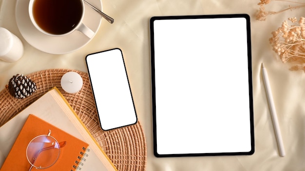Espace de travail féminin minimal confortable avec tablette et vue de dessus de maquette d'écran blanc de smartphone