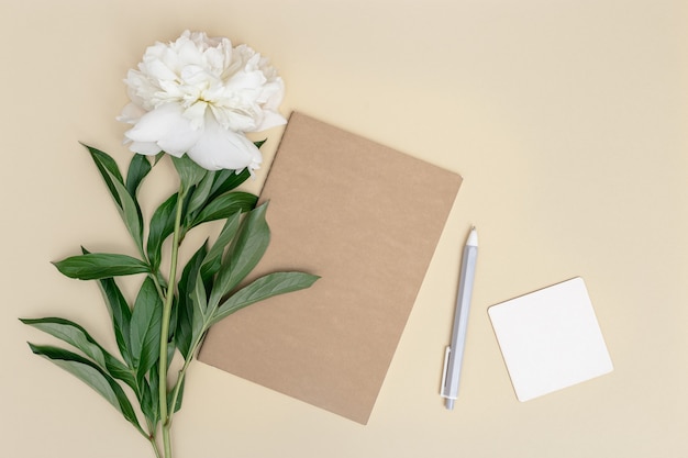 Espace de travail femme fermé stylo pour ordinateur portable fleur de pivoine blanche sur fond beige