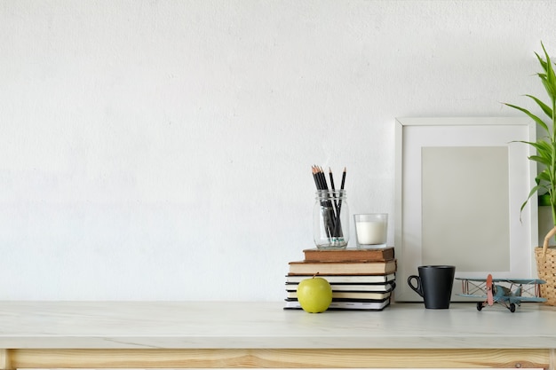 Espace de travail Loft avec une affiche vierge sur un bureau en bois blanc.