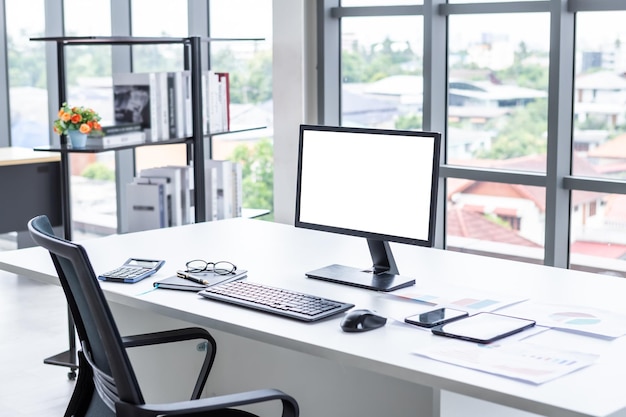 Photo espace de travail maquette d'ordinateur de bureau écran blanc vide avec clavier et autres accessoires sur un coin de bureau en bois sombre moderne et des chaises de bureau noires avec fenêtre à l'intérieur du bureau