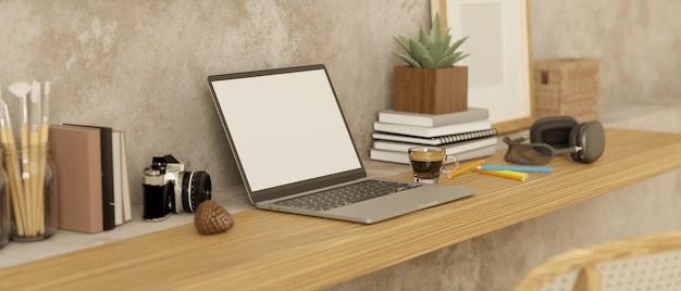 Espace de travail minimal avec des écouteurs de papeterie de livres de maquette d'ordinateur portable et un décor sur une table en bois