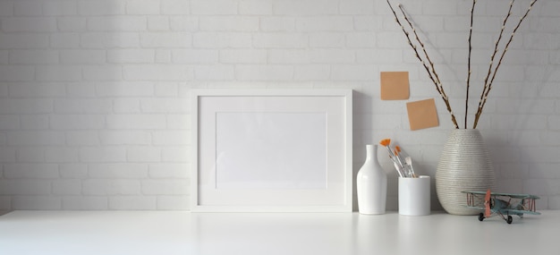 Espace de travail minimal avec espace de copie et cadre blanc avec des livres sur un tableau blanc et un mur blanc