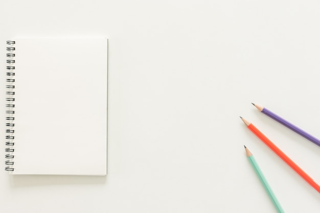 Espace de travail minimal - Photo créative de la table plate du bureau de l&#39;espace de travail avec un carnet de croquis et un crayon en bois sur un fond de copie fond blanc. Vue de dessus, photographie plate.