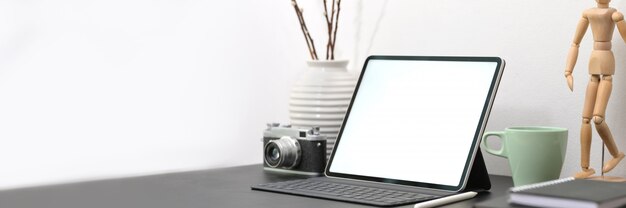 espace de travail minimaliste avec tablette, appareil photo, fournitures et décorations