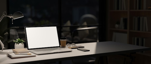 Espace de travail moderne avec maquette d'ordinateur portable sur table dans une pièce sombre moderne en arrière-plan