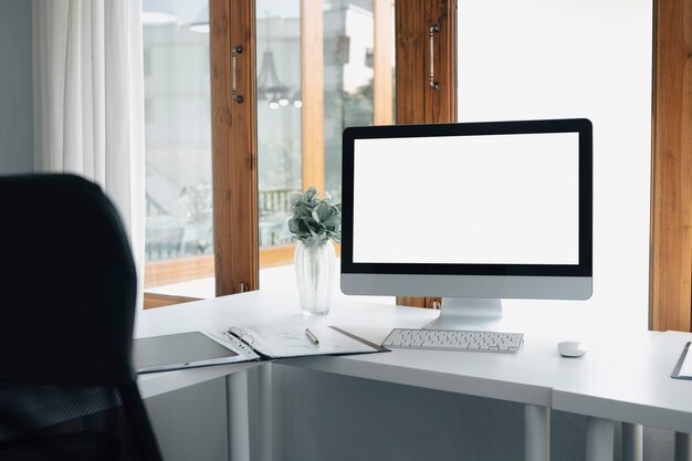 Espace de travail moderne avec ordinateur, plante en pot et chaise de bureau confortable.