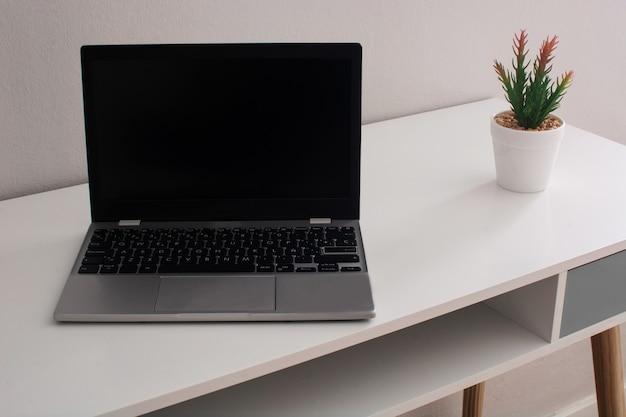 Espace de travail moderne avec ordinateur portable et fleur sur le bureau