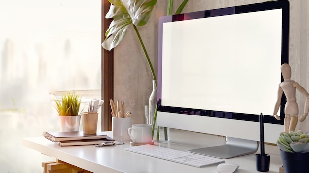 Espace de travail avec un ordinateur à écran blanc sur un tableau blanc