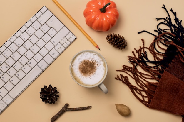 Espace de travail avec ordinateur portable ou clavier Crayon Écharpe confortable et chaude Citrouille Pomme de pin et tasse de café