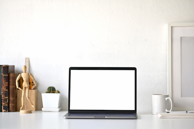 Espace de travail avec un ordinateur portable à écran blanc vierge sur le bureau loft.