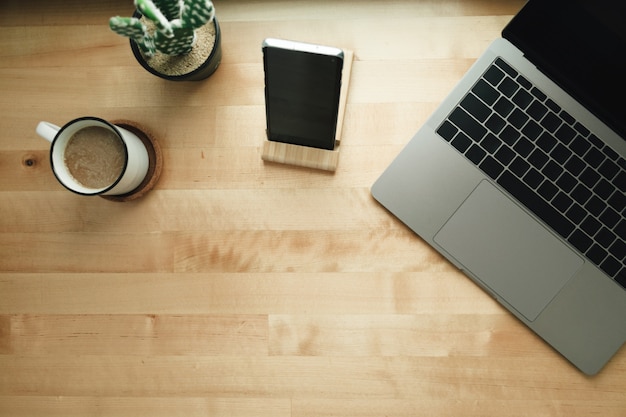 Espace de travail avec ordinateur portable et tasse de café sur un bureau en bois.