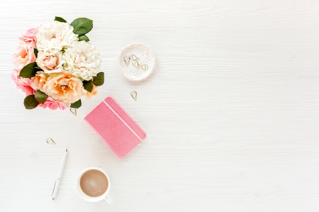 Espace de travail pour femmes avec accessoires de fleurs roses et beiges journal sur fond blanc plat vue de dessus mode féminine fond